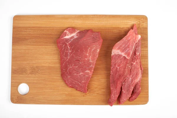 Peça de carne crua e fatias na placa de corte de madeira isolada no fundo branco — Fotografia de Stock