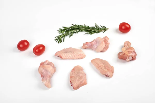 Asas de galinha cruas, tomates e alecrim isolados sobre fundo branco — Fotografia de Stock