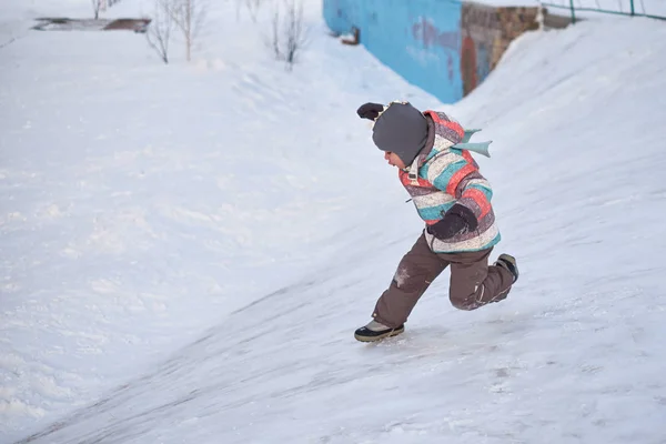 Rolig liten unge pojke i färgglada kläder spelar utomhus på vintern på kalla snöiga dagar. Lyckligt barn ha roligt och spela med snö — Stockfoto