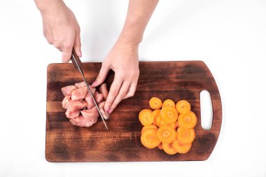 Beyaz arka plan üzerinde izole bir kesme tahtası üzerinde bir mutfak bıçağı ile ham Türkiye et ve havuç kesim