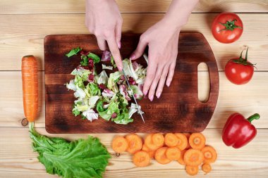 Yemek sebze salata ahşap arka plan üzerinde erkek doğrama yeşil salata, eller
