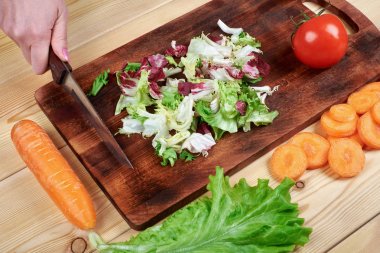 Yemek sebze salata ahşap arka plan üzerinde erkek doğrama yeşil salata, eller