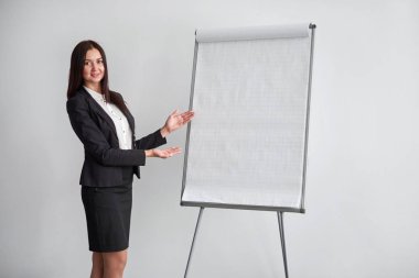 Flipchart Office yakın duran ve üzerinde işaret eden genç gülümseyen iş kadını portresi