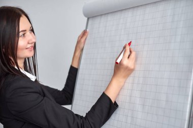 Güzel gülümseyen genç kadın onun bir sunu veya promosyon yaptığı gibi bir boş flipchart Office yazma