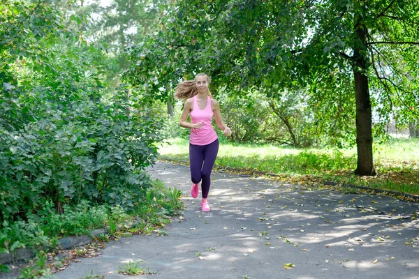 Attraktive junge Frau beim Joggen auf dem Parkweg. Konzept eines gesunden Lebensstils — Stockfoto