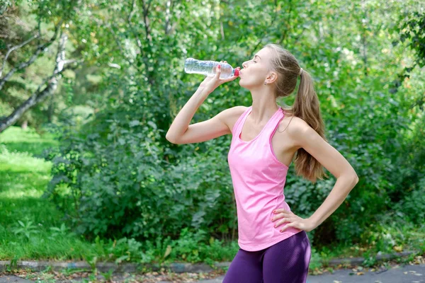 Jeune femme sportive buvant de l'eau de la bouteille. Faire du sport en plein air . — Photo