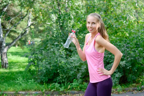 Jeune femme sportive buvant de l'eau de la bouteille. Faire du sport en plein air . — Photo
