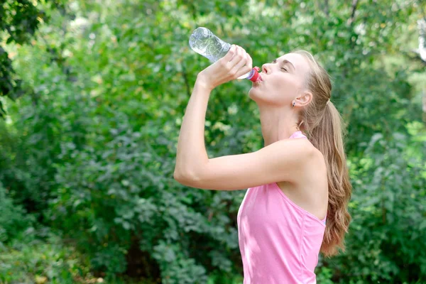 Jeune femme sportive buvant de l'eau de la bouteille. Faire du sport en plein air . — Photo