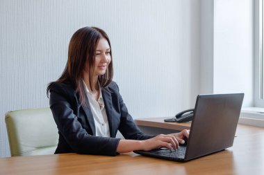 gülümseyen genç kadın ofiste bilgisayar üzerinde çalışan