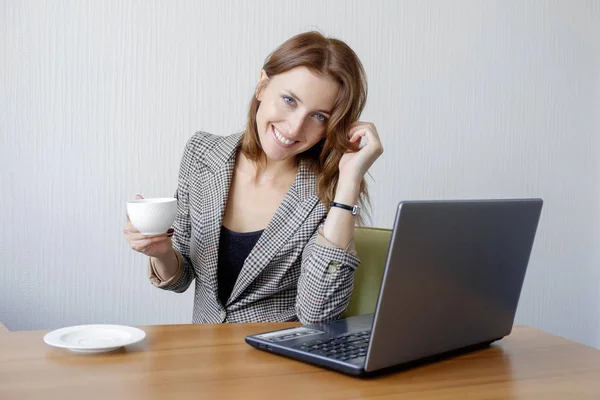 Nette junge Erwachsene arbeiten am Laptop am Schreibtisch neben der Kaffeetasse — Stockfoto