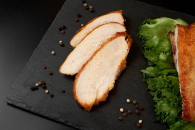 Kızarmış, dilimlenmiş tavuk göğsü siyah bir tabakta..