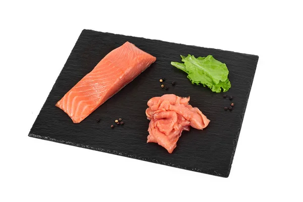 Sliced salmon fillet on the black shale board, with lemon and salad. On white background — Stock Photo, Image