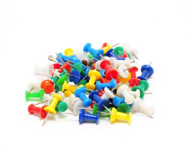 Beyaz arkaplanda çok renkli ofis raptiyeleri yığını.