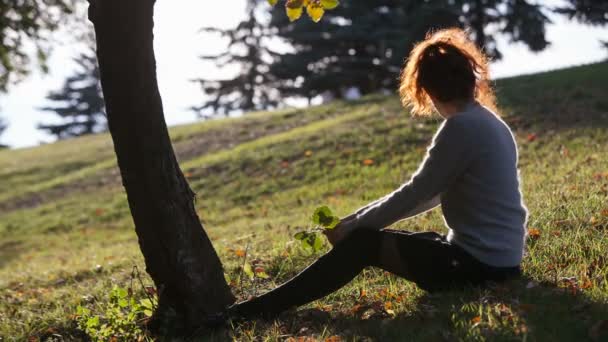 Jonge dame zitplaatsen op het gras — Stockvideo