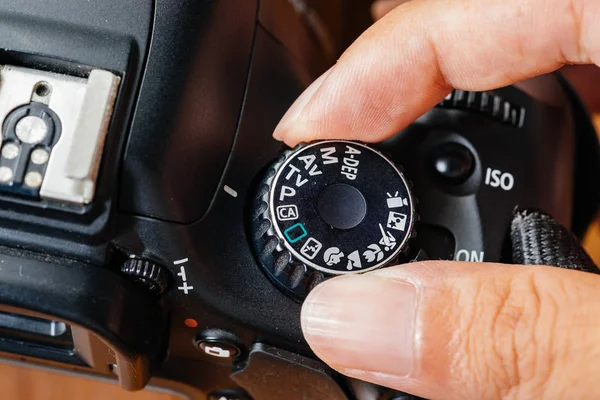 Programma kiezen modus op dslr camera met vingers op de wijzerplaat — Stockfoto