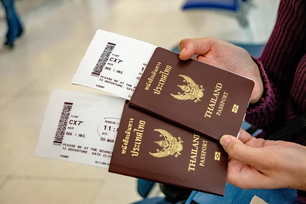 Dua paspor Thailand di tangan dengan boarding pass Stok Lukisan  