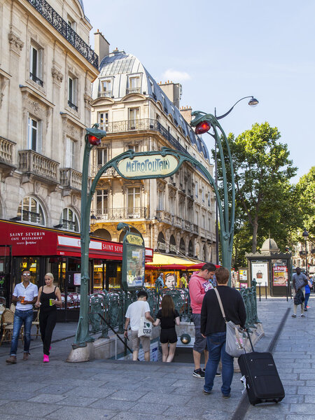 Париж, Франция, 9 июля 2016 г. Типичный вид на город. Люди идут по улице рядом со входом в метро, станция Сен-Мишель
