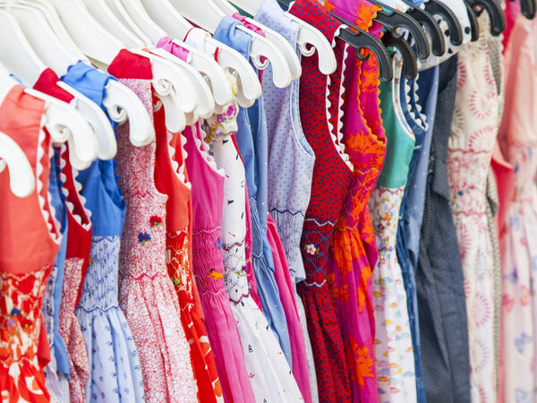 Разноцветные детские платья на витрине магазина
