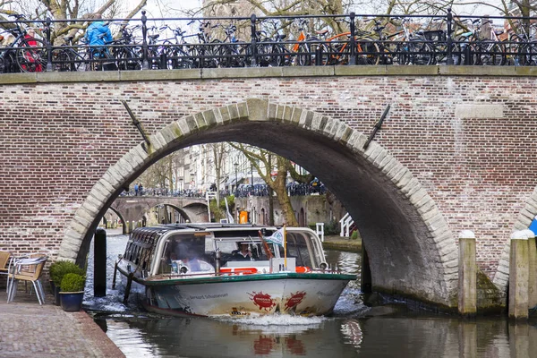 Utrecht, Nizozemsko, 30. března 2016. Kanál oblast. Malebný starý kamenný most. Chůze loď plave — Stock fotografie