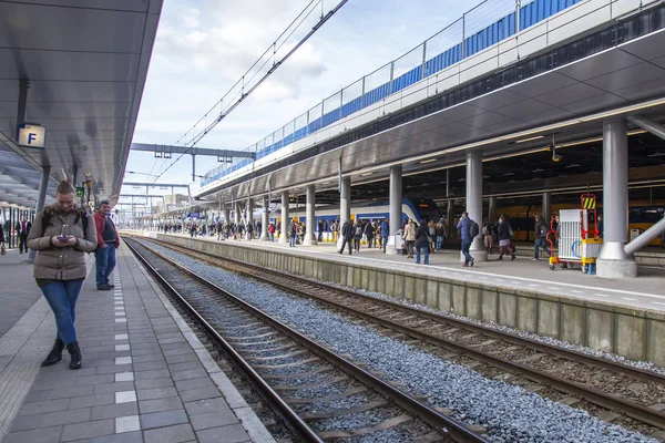 Utrecht, Nederländerna, den 30 mars 2016. Passagerarna väntar på tåget på plattformen av järnvägsstationen — Stockfoto