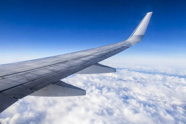 Крыло летающего самолета на фоне неба и облаков — стоковое фото