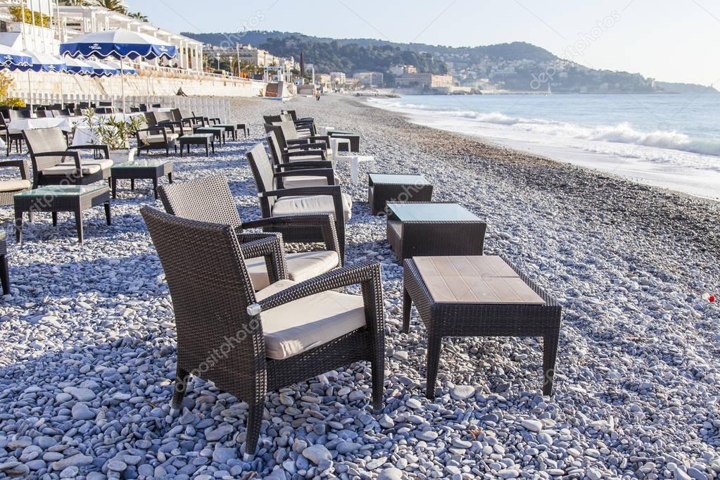 NICE, FRANCE, on JANUARY 9, 2017. The morning sun lights Promenade des Anglais - the main embankment of the city, one of the most beautiful in the world, and little tables of cafe on the city pebble beach