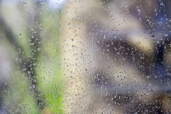 Udsigt gennem fugtigt glas med regndråber - Stock-foto