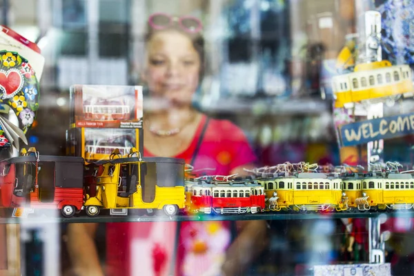 LISBON, PORTUGAL, 22 июня 2017 года. Молодая привлекательная женщина рассматривает традиционные сувениры на витрине магазина за стеклом — стоковое фото
