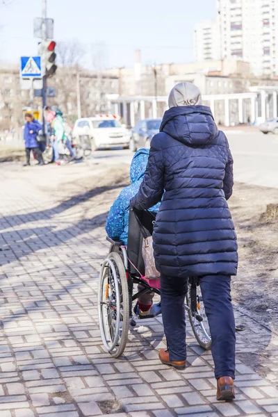 Pushkino, Oroszország, a március 25-én, 2017. A nő tolja a kerekesszék, az utcán a belvárosban — Stock Fotó