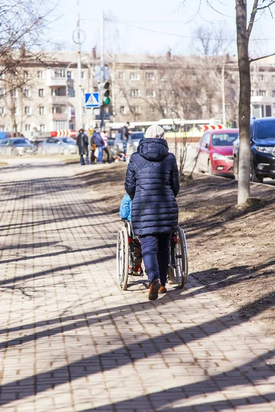 Pushkino, Rusya, üzerinde 25 Şubat 2017. Kadın sokakta tekerlekli şehir merkezinde iter.