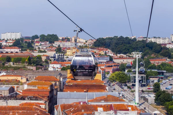 PORTO, PORTUGAL, 15 de junio de 2017. Día de verano. El sol ilumina los tejados rojos del centro de la ciudad en la orilla del río Duero. Una cabaña de Teleferiko recorre casas — Foto de Stock