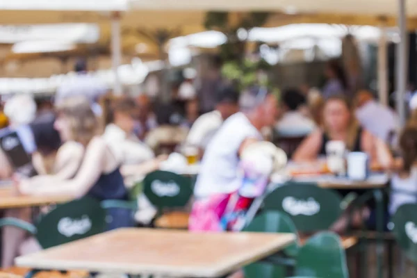 Blurred image. People eat and have a rest in cafe under the open sky in the European city.