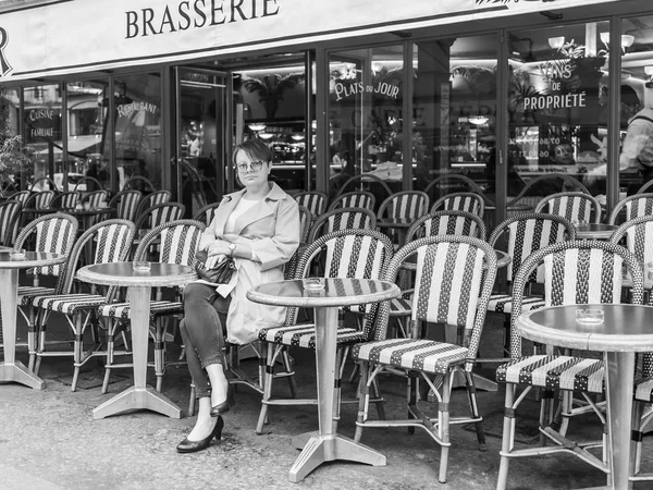 Paříž, Francie, na 27 října 2017. Žena sedí na stolku typické kavárny v Pařížské ulici v noci. — Stock fotografie