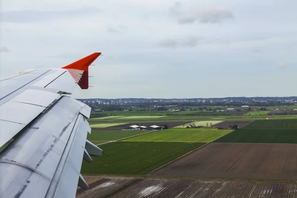 Vista desde la ventana del avión volador en un ala y la superficie de tierra debajo — Foto de Stock