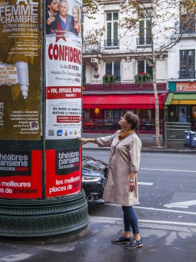 Paris, Fransa, üzerinde 27 Ekim 2017. Kadın sokakta bir curbstone afişlerde denetler
