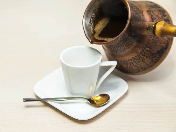 古代銅コーヒー ポットからエスプレッソ コーヒーの白磁のカップにコーヒーを注いだ — ストック写真