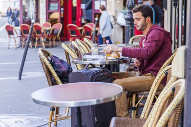 Paris, Fransa, üzerinde 30 Ekim 2017. Genç adam sabah Paris sokaklarda tipik kafe küçük bir masada oturur. 