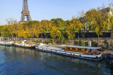 PARIS, FRANCE, on October 30, 2017. Autumn city landscape. The sunset sun lights the river Seine and its embankments. Manned barges are moored to the coast. Eiffel Tower in the distance clipart