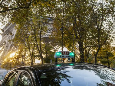 Paris, Fransa, üzerinde 27 Ekim 2017. Taksi araba sokak şehir olacak. Eyfel Kulesi ile uzaktan ağaçların arkasında günbatımı güneş yaktı