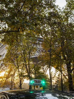 Paris, Fransa, üzerinde 27 Ekim 2017. Taksi araba sokak şehir olacak. Eyfel Kulesi ile uzaktan ağaçların arkasında günbatımı güneş yaktı