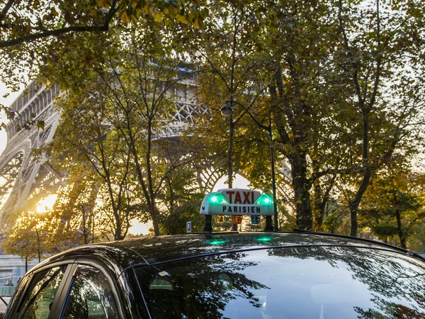 Paris, Fransa, üzerinde 27 Ekim 2017. Taksi araba sokak şehir olacak. Eyfel Kulesi ile uzaktan ağaçların arkasında günbatımı güneş yaktı
