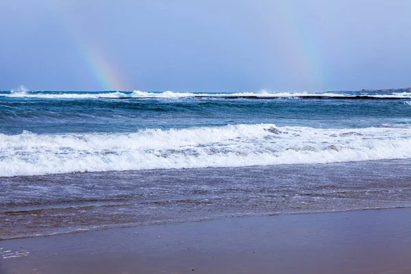 View of the line of a surf and rainbow in the distance