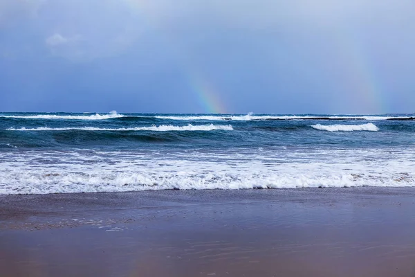 View of the line of a surf and rainbow in the distance