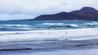 Las Palmas de Gran Canaria, İspanya, 6 Ocak 2018 üzerinde. Kış Güneşi Playa de Las Canteras beach Atlantik Okyanusu kıyısında ışıklar. Sörfçü dalgalar binmek