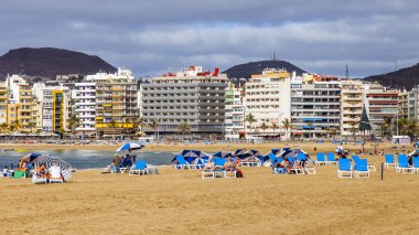 Las Palmas de Gran Canaria, İspanya, 6 Ocak 2018 üzerinde. Waterfront mesafe ve Atlantik okyanus kıyısında Playa de Las Canteras plaj kış bilir. İnsanlar biraz dinlen ve şezlong içinde güneşlenmek