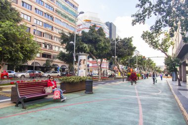 Las Palmas de Gran Canaria, İspanya, 5 Ocak 2018 üzerinde. Şehir merkezindeki eski ağaçlar güzel Caddesi. Kadının bir dinlenme bir bankta yok.