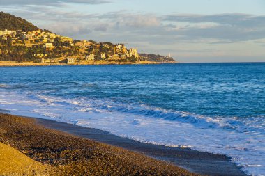 Güzel, Fransa, 6 Mart 2018. Günbatımı güneş dağ onun kıyısında dalgalar deniz sörf pitoresk bir koyda ve Bina Işıkları