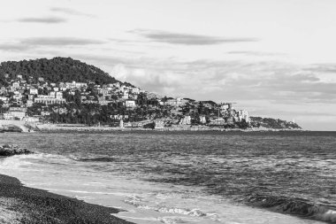 Güzel, Fransa, 6 Mart 2018. Günbatımı güneş dağ onun kıyısında dalgalar deniz sörf pitoresk bir koyda ve Bina Işıkları