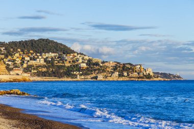 Güzel, Fransa, 6 Mart 2018. Günbatımı güneş dağ onun kıyısında dalgalar deniz sörf pitoresk bir koyda ve Bina Işıkları