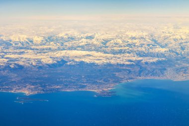 Deniz kıyısı bir sis içinde engebeli arazide. Büyük yükseklikte uçan uçak penceresinden bir görünüm
